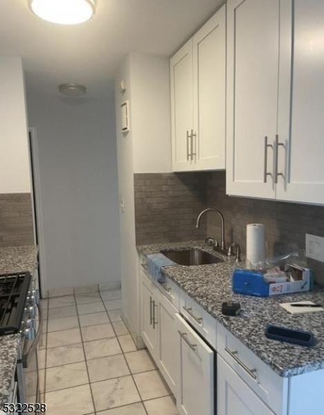 kitchen featuring white cabinets, decorative backsplash, and a sink
