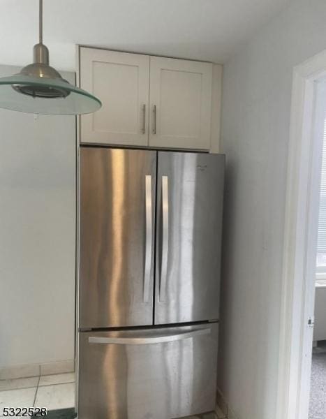 kitchen view of freestanding refrigerator and white cabinetry