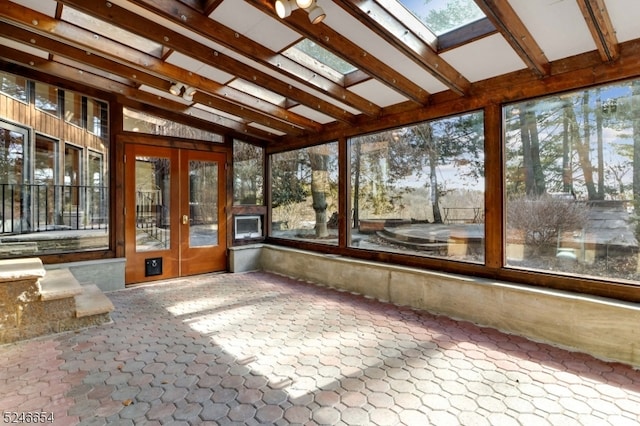 unfurnished sunroom with french doors, vaulted ceiling with skylight, and a healthy amount of sunlight