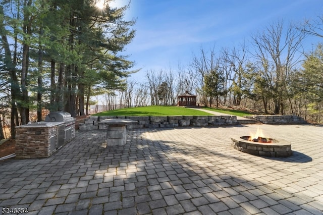 view of patio with a gazebo, a fire pit, a grill, and an outdoor kitchen