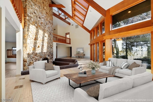 living room with beamed ceiling, light hardwood / wood-style flooring, baseboard heating, and high vaulted ceiling