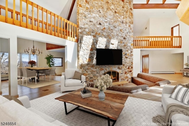 living room featuring high vaulted ceiling, a baseboard heating unit, a stone fireplace, hardwood / wood-style flooring, and a chandelier