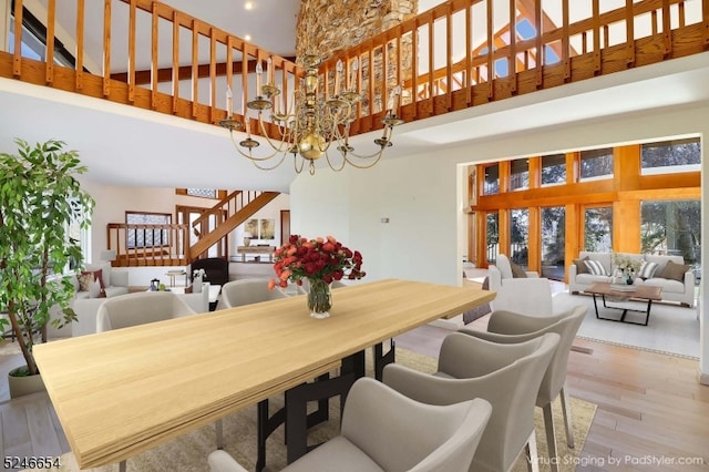 dining space with a notable chandelier, hardwood / wood-style flooring, and a high ceiling