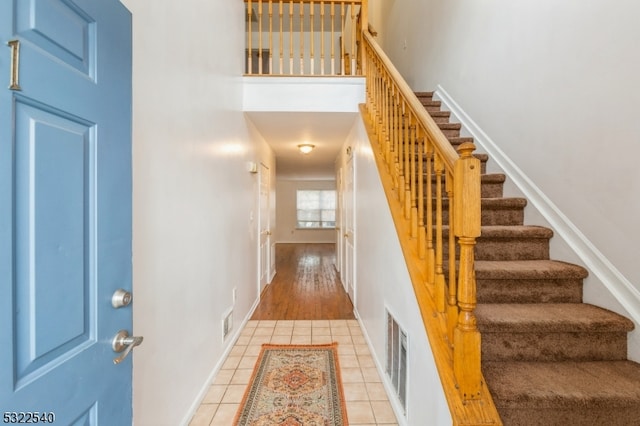 stairway featuring tile patterned flooring and a high ceiling