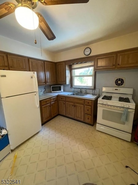 kitchen featuring white appliances, ceiling fan, and sink