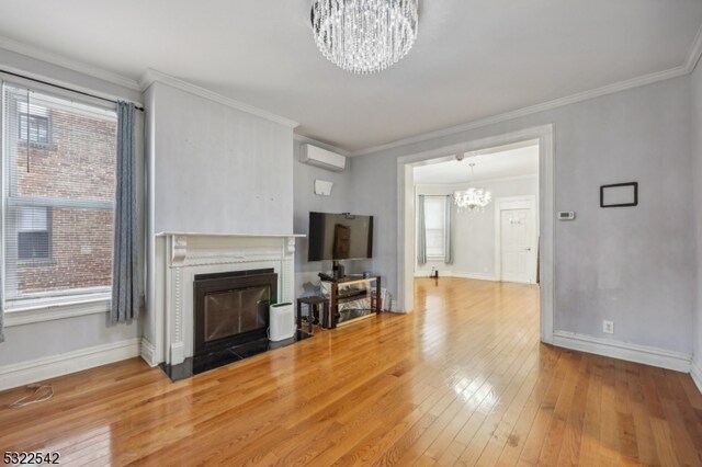 living room with a wall mounted AC, ornamental molding, hardwood / wood-style flooring, and a chandelier