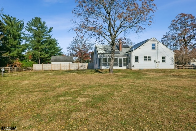 rear view of house featuring a sunroom and a lawn