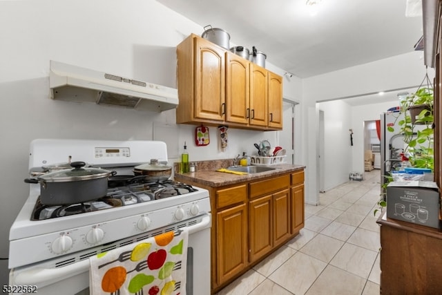 kitchen with light tile patterned flooring, extractor fan, sink, and white range with gas stovetop