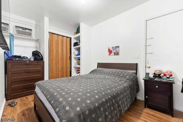 bedroom with light hardwood / wood-style floors, a closet, and a wall mounted air conditioner