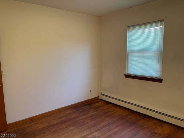 empty room featuring dark hardwood / wood-style floors and a baseboard radiator