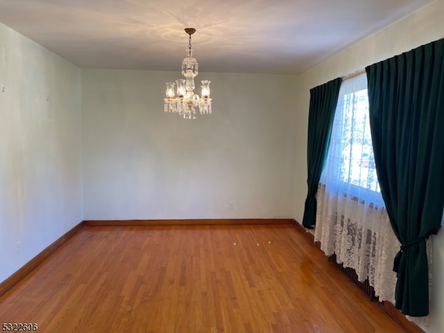 spare room featuring an inviting chandelier and wood-type flooring