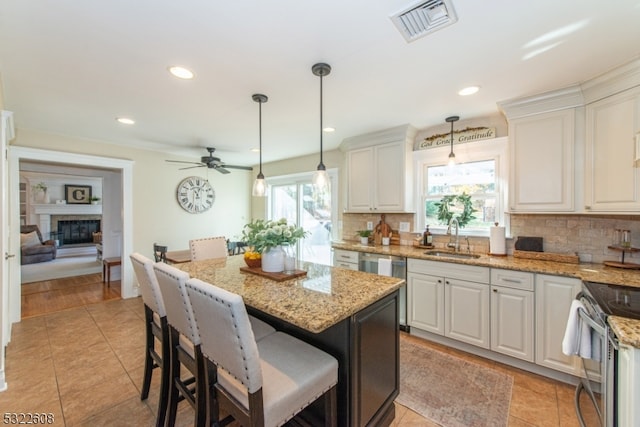 kitchen with white cabinetry, sink, backsplash, decorative light fixtures, and a center island