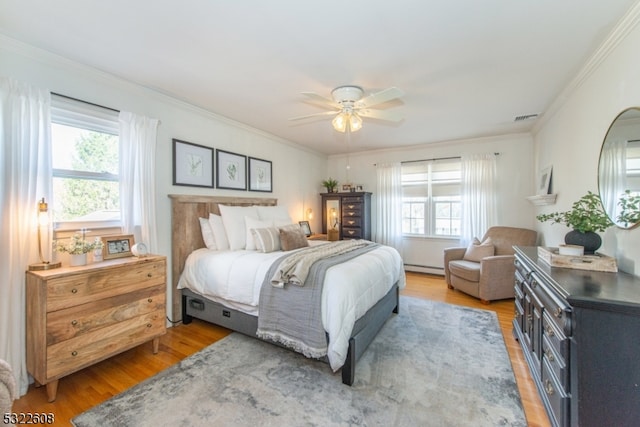 bedroom featuring ceiling fan, multiple windows, hardwood / wood-style flooring, and ornamental molding