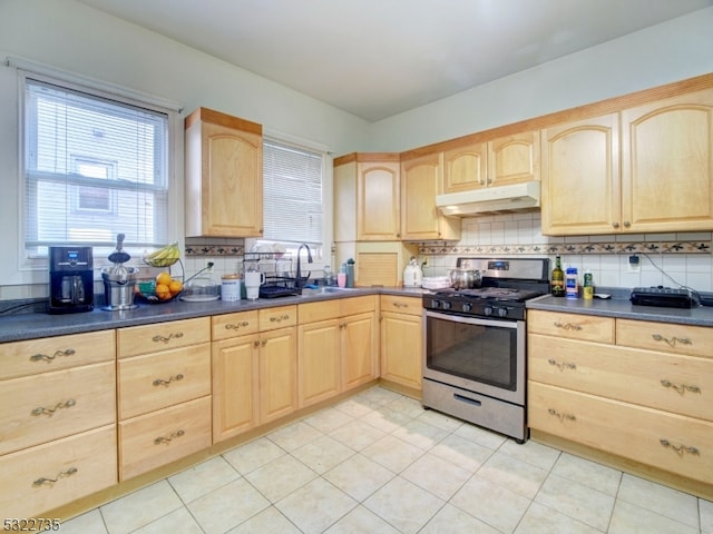 kitchen with sink, tasteful backsplash, stainless steel gas stove, light tile patterned flooring, and light brown cabinetry