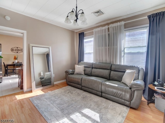 living room featuring hardwood / wood-style flooring, crown molding, and a notable chandelier