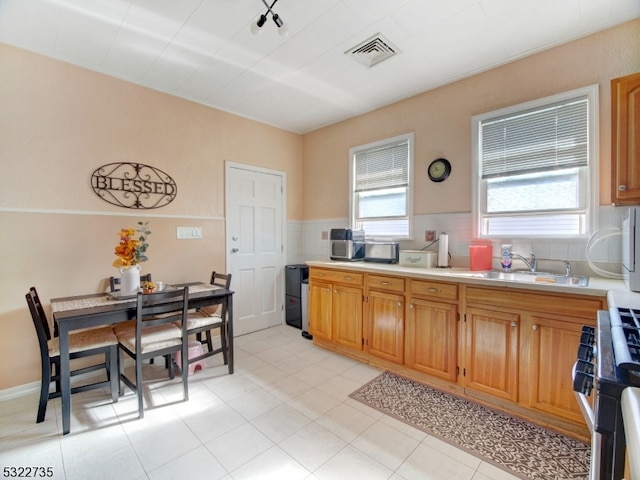 kitchen featuring light tile patterned floors, stainless steel gas range oven, and sink