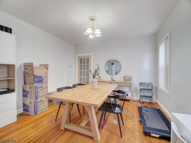 dining space with hardwood / wood-style floors and a notable chandelier