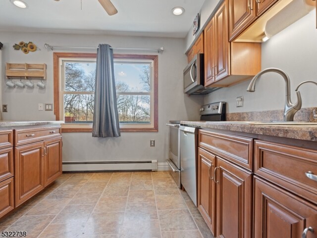 kitchen with baseboard heating, stainless steel appliances, sink, and ceiling fan