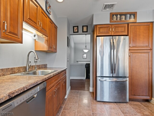 kitchen featuring appliances with stainless steel finishes, sink, light tile patterned floors, and hanging light fixtures