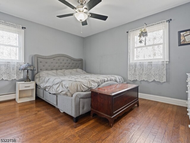 bedroom with baseboard heating, multiple windows, dark hardwood / wood-style floors, and ceiling fan