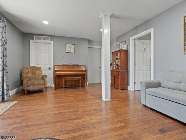 sitting room featuring decorative columns and light hardwood / wood-style floors