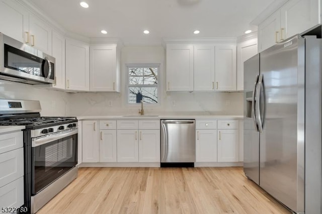 kitchen featuring backsplash, white cabinets, sink, light hardwood / wood-style flooring, and stainless steel appliances