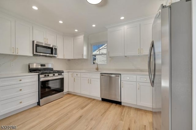 kitchen featuring sink, white cabinetry, stainless steel appliances, and light wood-type flooring