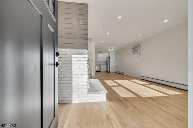 interior space featuring light wood-type flooring, a wall mounted AC, and a baseboard radiator