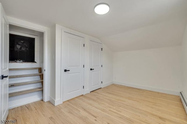 bonus room with light wood-type flooring, baseboard heating, and vaulted ceiling