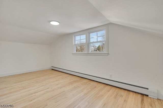 additional living space with light wood-type flooring, lofted ceiling, and baseboard heating