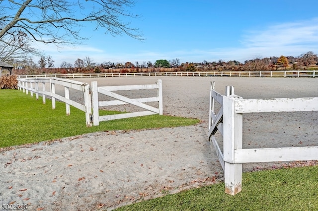 view of gate with a lawn and a rural view