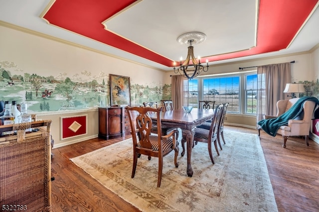 dining room with dark hardwood / wood-style floors, a tray ceiling, and an inviting chandelier