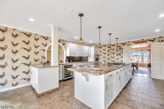 kitchen featuring a kitchen island with sink, pendant lighting, and beverage cooler