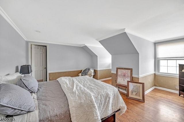 bedroom with light hardwood / wood-style floors, lofted ceiling, and crown molding