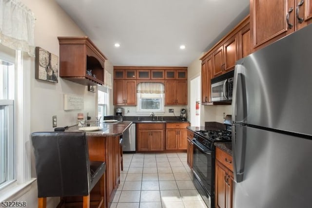 kitchen with glass insert cabinets, appliances with stainless steel finishes, brown cabinetry, and a sink