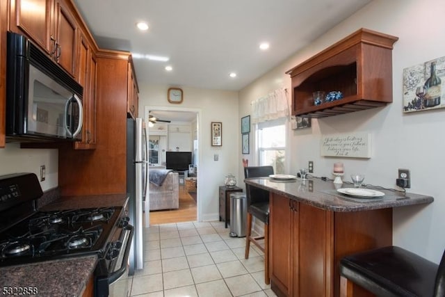 kitchen with stainless steel appliances, dark stone countertops, brown cabinets, and a kitchen breakfast bar