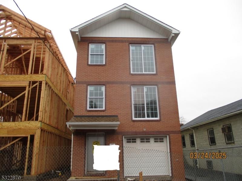 back of house with brick siding and an attached garage