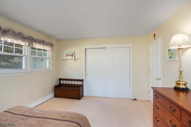 bedroom featuring light carpet, baseboards, baseboard heating, and a closet