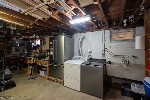 unfinished basement featuring washing machine and dryer, a sink, stainless steel refrigerator with ice dispenser, and a workshop area