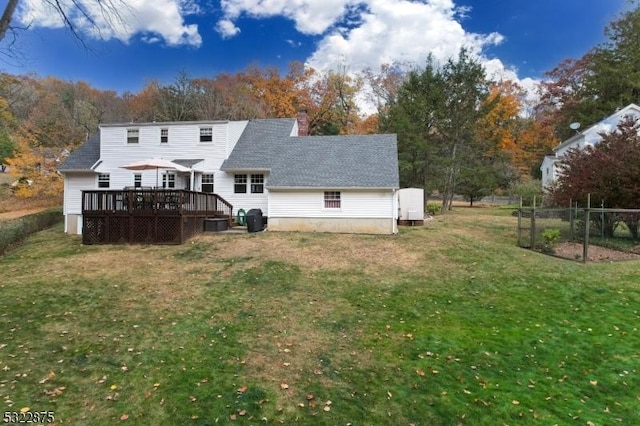 rear view of house featuring a shingled roof, a chimney, fence, a deck, and a yard