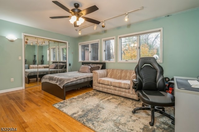 bedroom featuring a closet, rail lighting, ceiling fan, and light hardwood / wood-style flooring