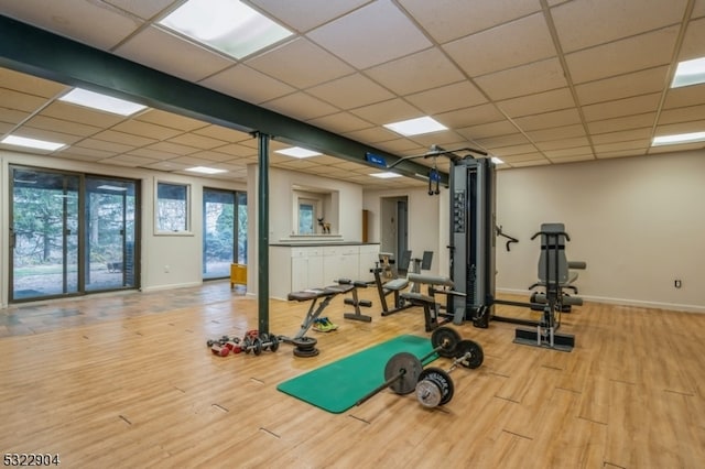 workout area featuring light wood-type flooring and a paneled ceiling