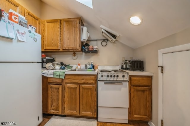 kitchen with light hardwood / wood-style floors, lofted ceiling, sink, and white appliances