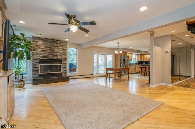 unfurnished living room featuring a baseboard heating unit, light wood-type flooring, a fireplace, and ceiling fan with notable chandelier