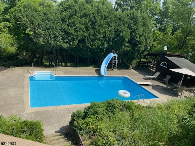 view of pool with a diving board, a patio area, and a water slide