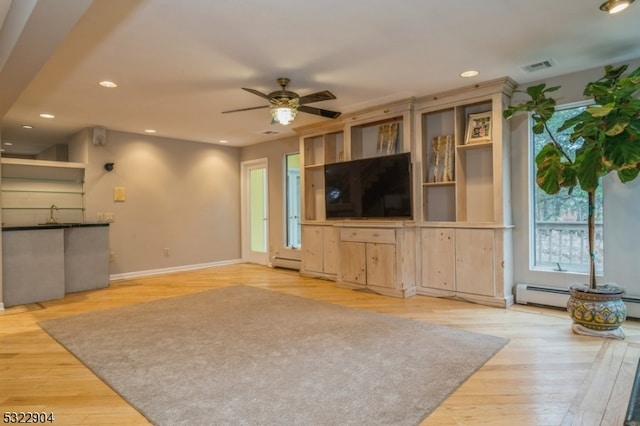 unfurnished living room with ceiling fan, baseboard heating, and light hardwood / wood-style floors