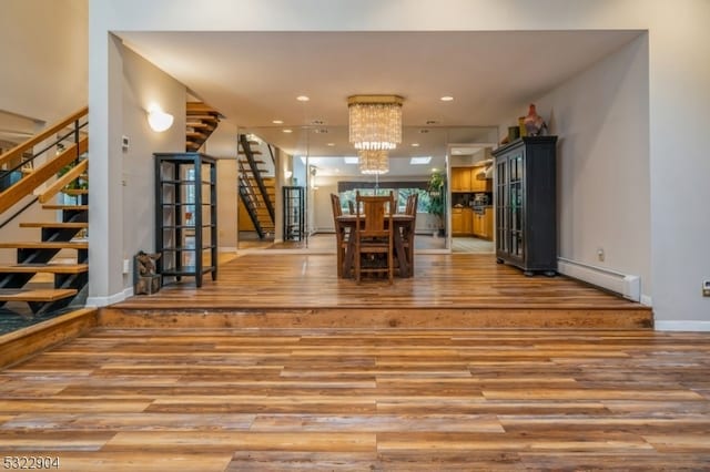 interior space featuring wood-type flooring, a baseboard radiator, and a chandelier