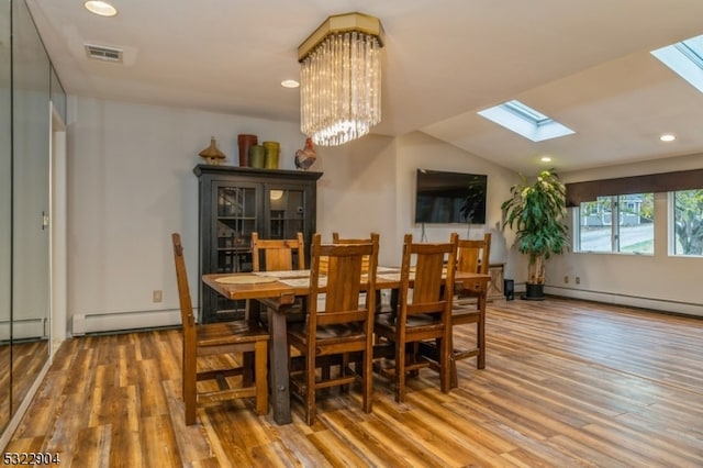 dining space with lofted ceiling with skylight, wood-type flooring, a notable chandelier, and a baseboard heating unit