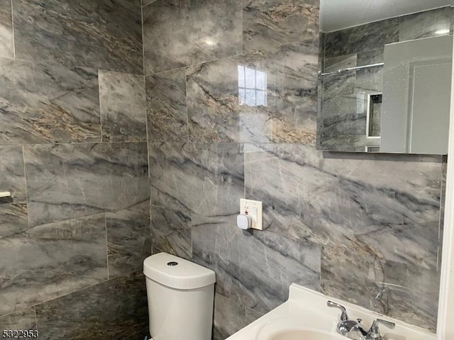 bathroom featuring toilet, sink, and tile walls