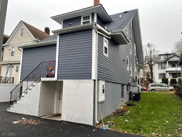 view of side of home with central air condition unit and a lawn